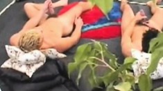Two horny studs lie side-by-side in bed for a synchronized masturbation session